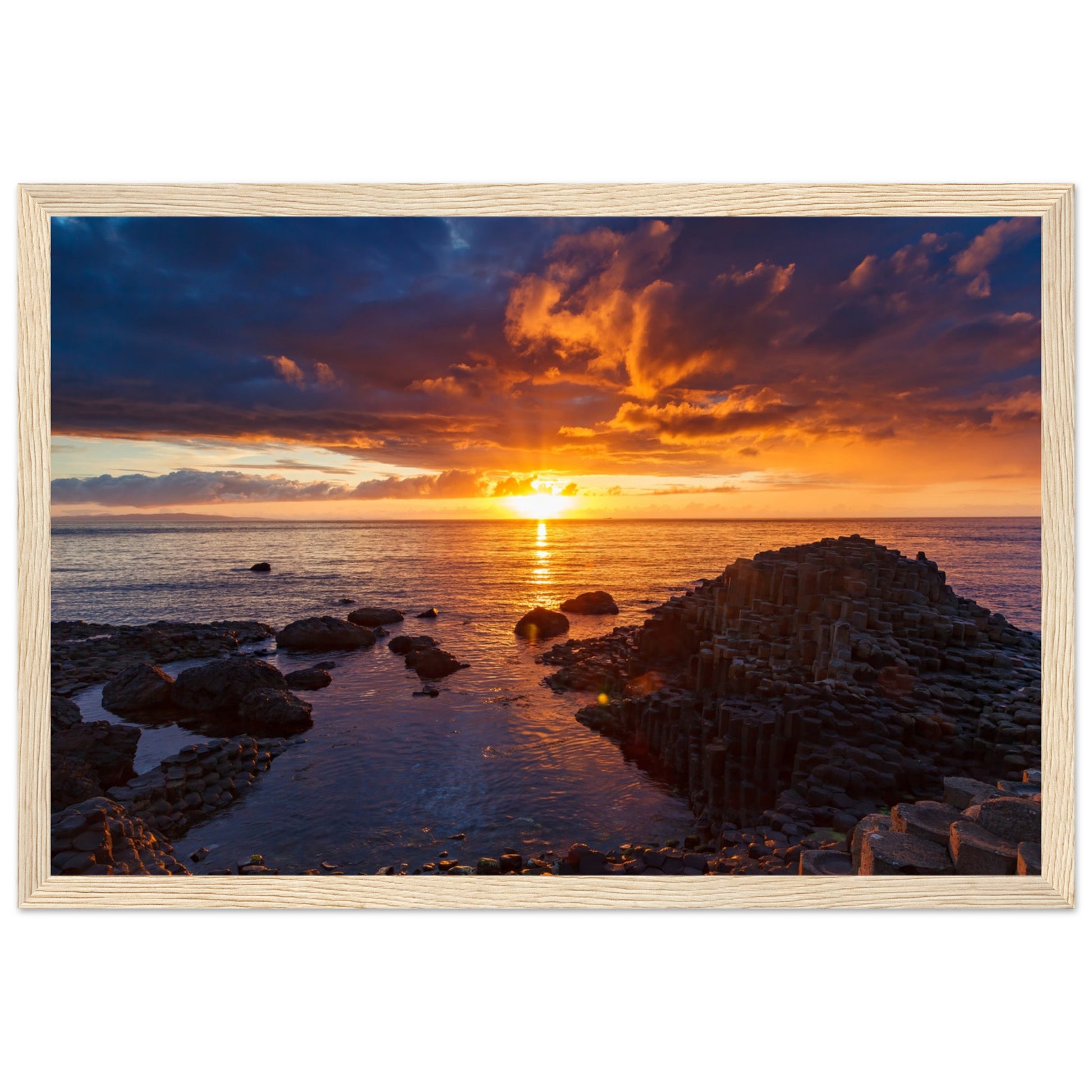 Framed art print of a mesmerizing sunset at Giant's Causeway, showcasing iconic basalt columns against a sky painted with warm hues. The scene captures nature's beauty and tranquility, adding a sophisticated touch to home or office decor. Perfect for any art lover.