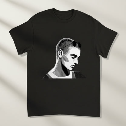 Premium unisex T-shirt in black featuring a stylised portrait of Sinead O’Connor. Neutral studio backdrop, soft side lighting, high-contrast detail on print.